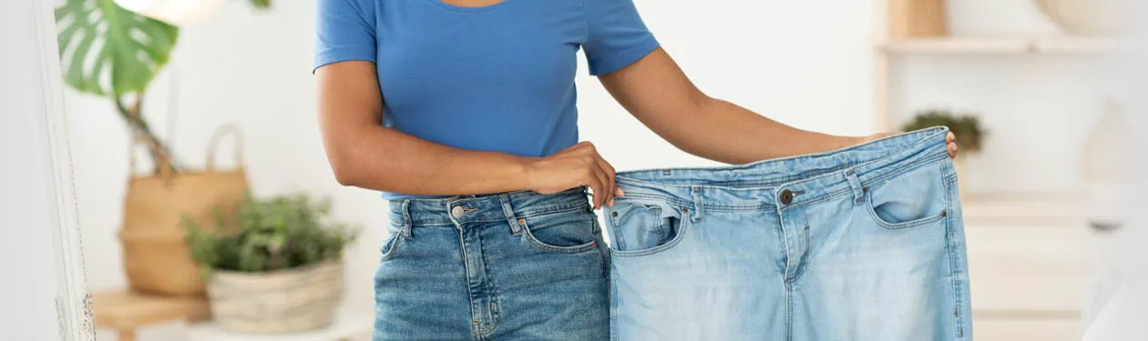 Bariatric surgery patient holding large jeans